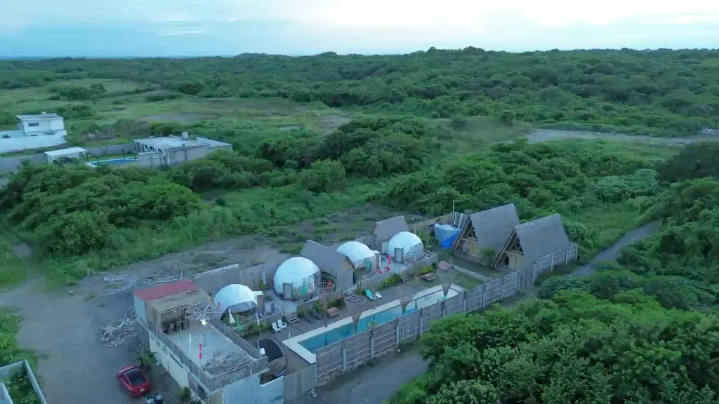 Vista aérea del glamping: los domos, las cabañas de palma y la alberca rodeados de vegetación