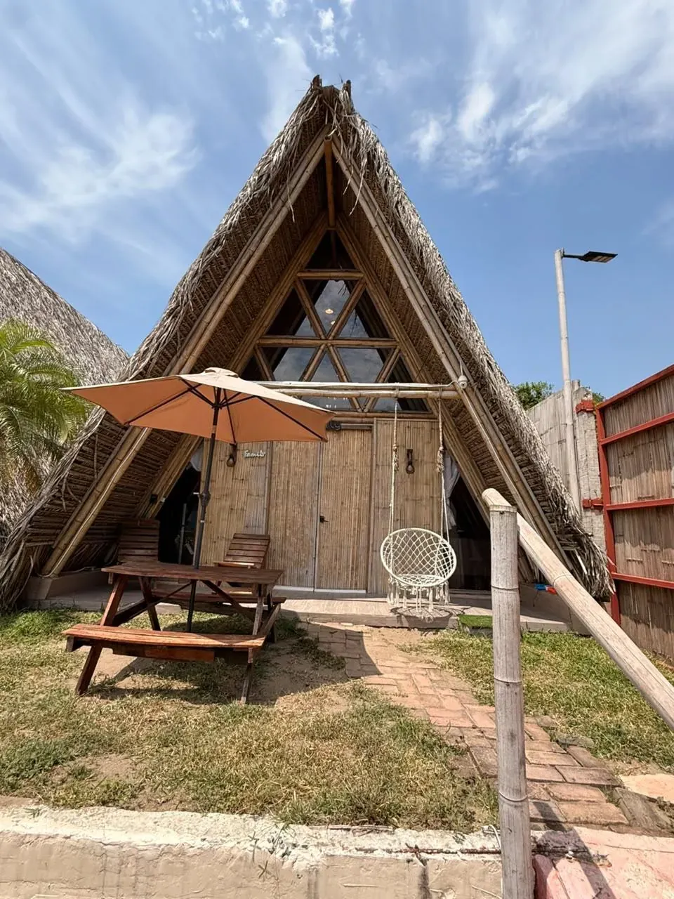 Cabaña tipo A de palma con mesa de picnic y silla colgante